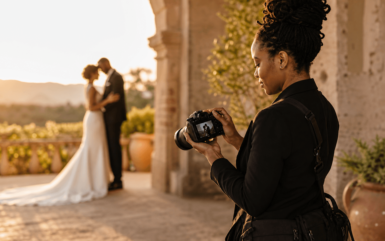 Professional Black woman wedding photographer reviewing a portrait during a golden-hour wedding session